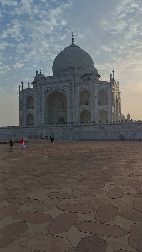 Side view of the Taj Mahal with people in colorful attire in foreground.