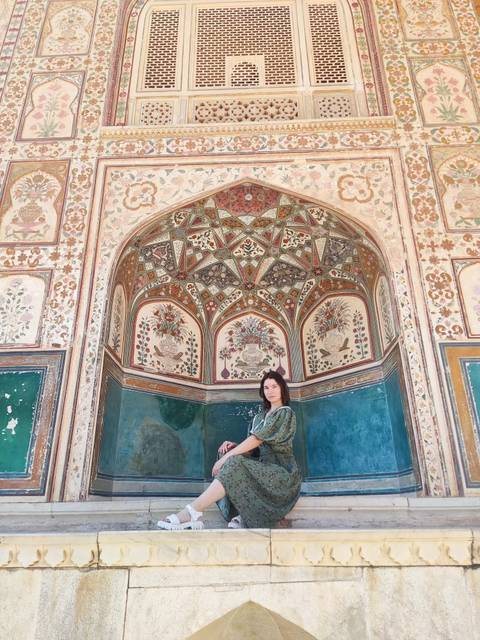 Woman in green dress in front of ornate archway.
