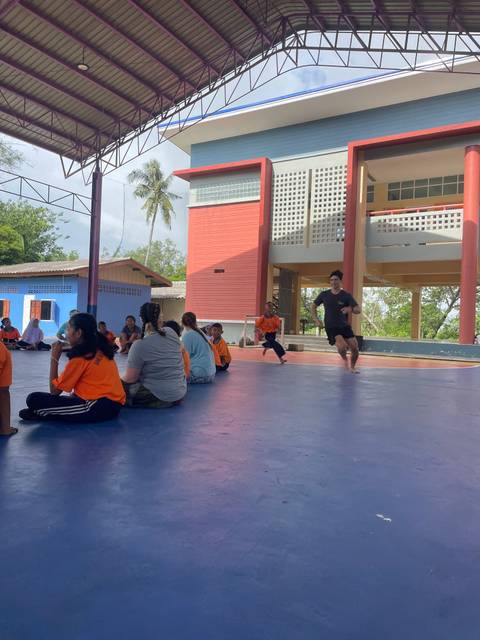 Several people participating in an indoor activity, some running.