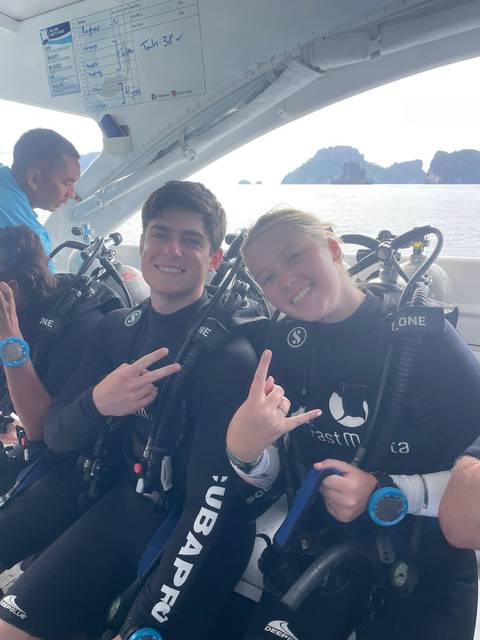 Two scuba divers smiling on a boat.