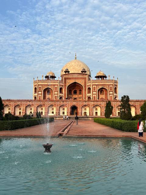 Humayun's Tomb with fountain and people walking in the garden area.