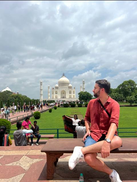 Person looking towards the Taj Mahal with others in the background.