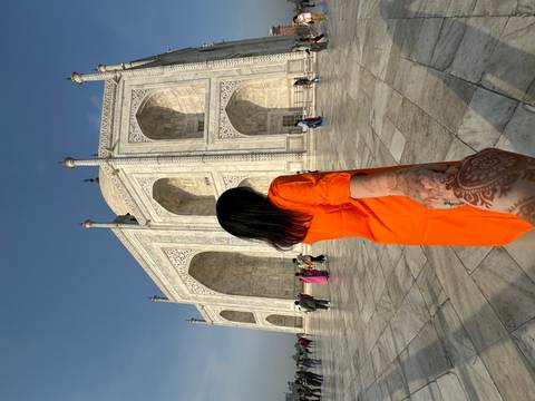 Person leading towards the Taj Mahal, hand extended, with intricate henna design.