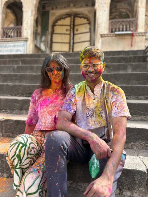 Two people covered in colorful powders, celebrating Holi.