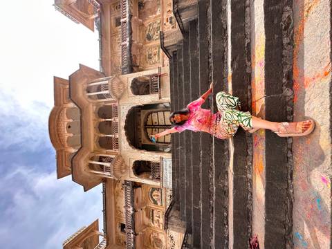 Person sitting on stairs of an old building covered in Holi powders.