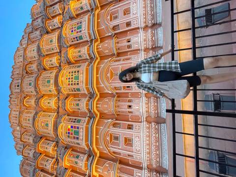 Person posing in front of Hawa Mahal with vibrant pastel colors.