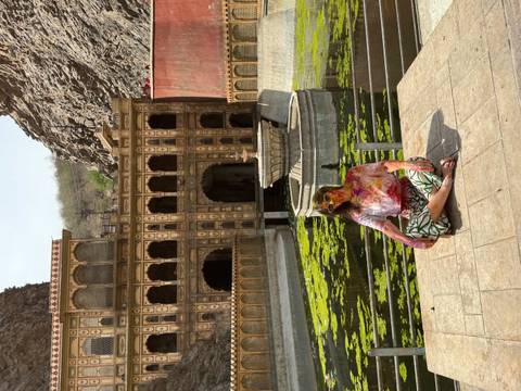 Person sitting in front of a historical building with a water fixture.