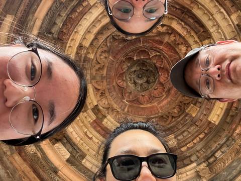 Group selfie with intricate ceiling design in the background.