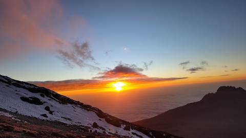      Beautiful sunrise view from a mountain with snowy peaks and clouds.
  