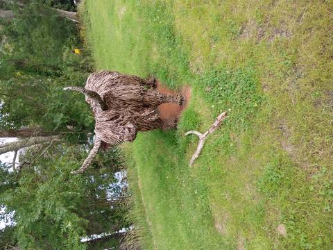       Sculpture of a Highland cow made of natural materials.
  