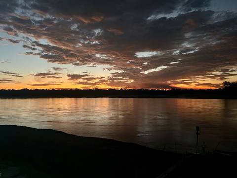 Sunset over a river with dramatic clouds.