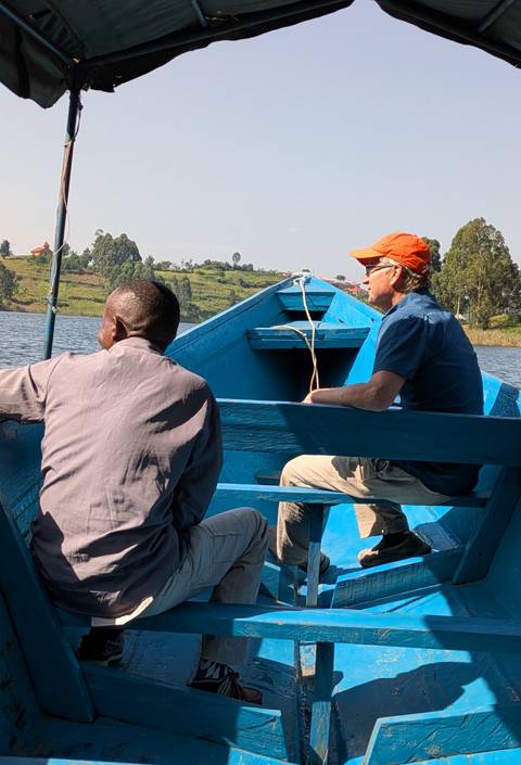 Two people in a blue boat, in a lake or river setting.