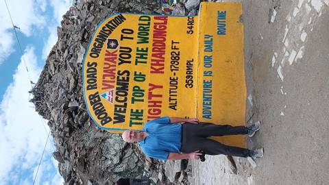 Person standing beside a signboard at Khardung La Pass.