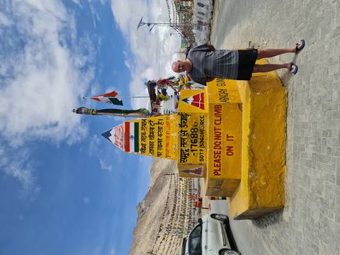 Person next to a monument with text in a mountainous area.