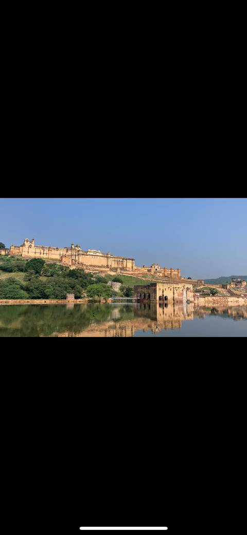 Amber Fort reflected in a water body with a blue sky.