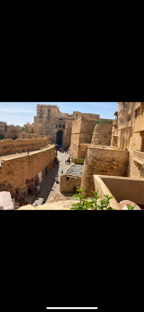 View of Jaisalmer Fort with people walking on a narrow street.