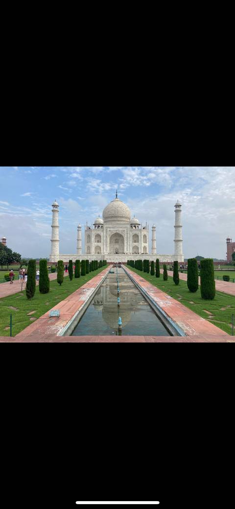 The Taj Mahal with tourists and a reflecting pool.