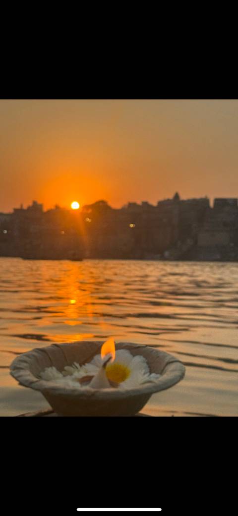 Sunset over a water body with silhouette of buildings.