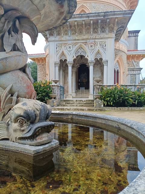 Ornate building facade with stone fountain in foreground.