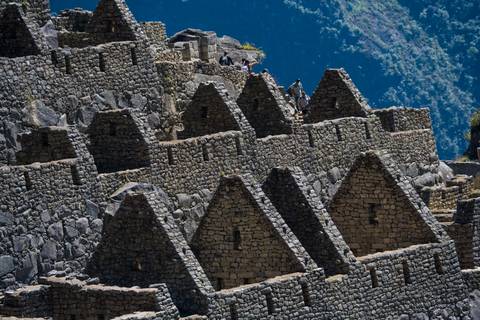 Stone buildings on a hillside with mountains.