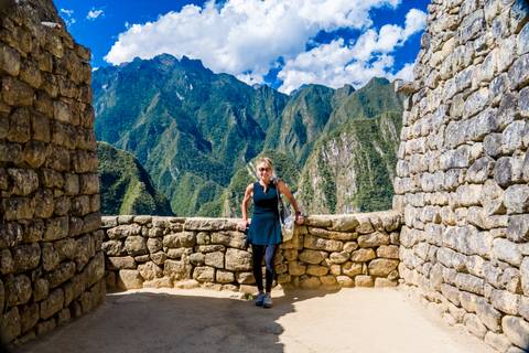 Woman posing between stone walls with mountain view.
