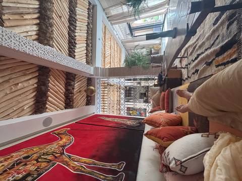       Interior of a traditional Moroccan room with a person lounging.
  