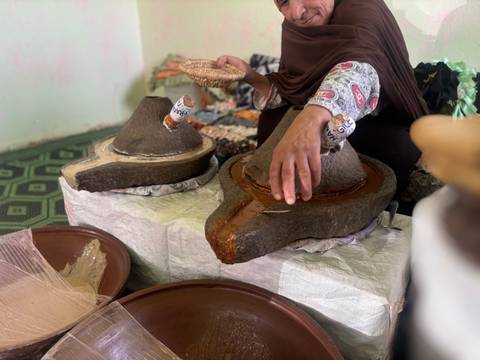      Woman working with traditional tools for oil extraction.
  