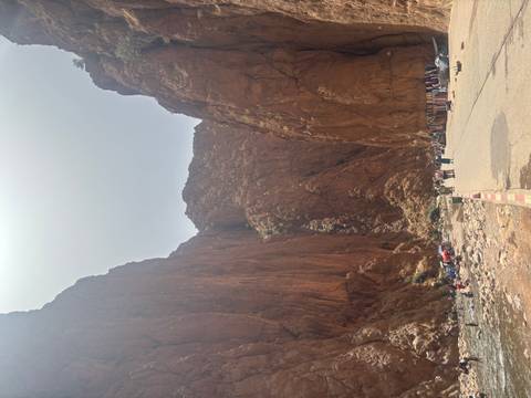       Narrow gorge with high cliffs and a pathway with people.
  