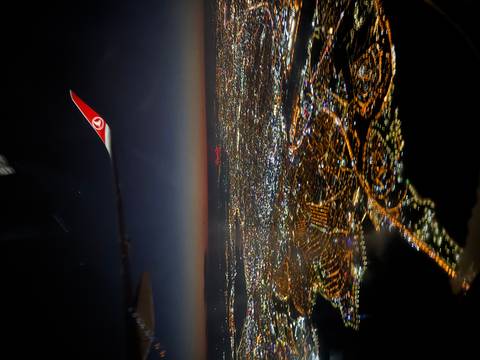       Aerial view of a city at night with an airplane wing.
  