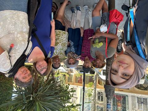       Group of people posing outdoors next to a tour bus.
  