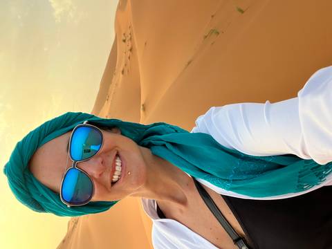 Woman wearing a headscarf and sunglasses in a desert.