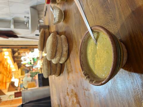 A bowl of soup and traditional bread on a wooden table in a rustic setting.