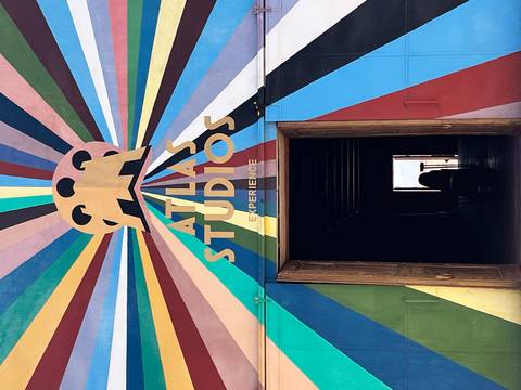       Entrance to Atlas Studios with a colorful mural and partially open doors.
  