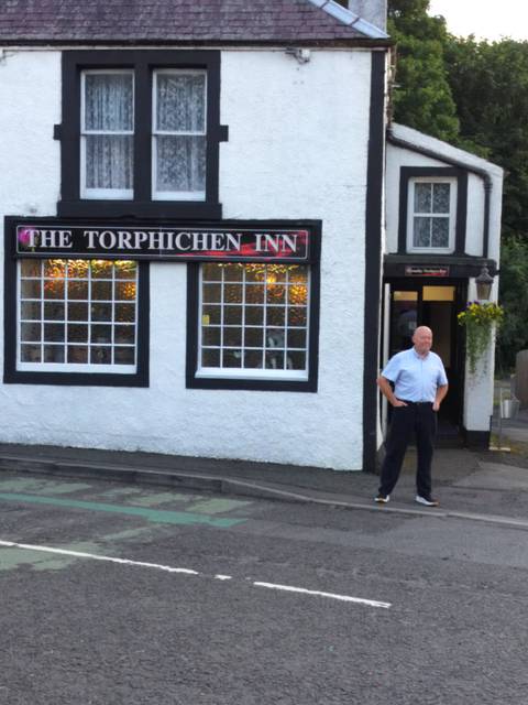 Blurry image of The Torphichen Inn and a person standing outside.
