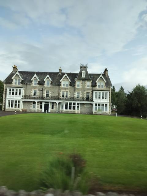 Large country house with lush green lawn.