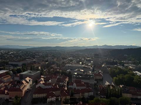       Aerial view of a city with sun setting behind mountains.
  