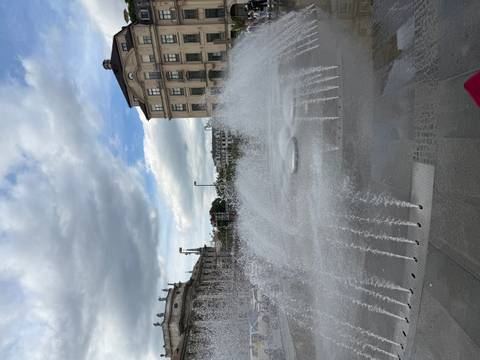       Fountain with water jets and buildings in the background.
  
