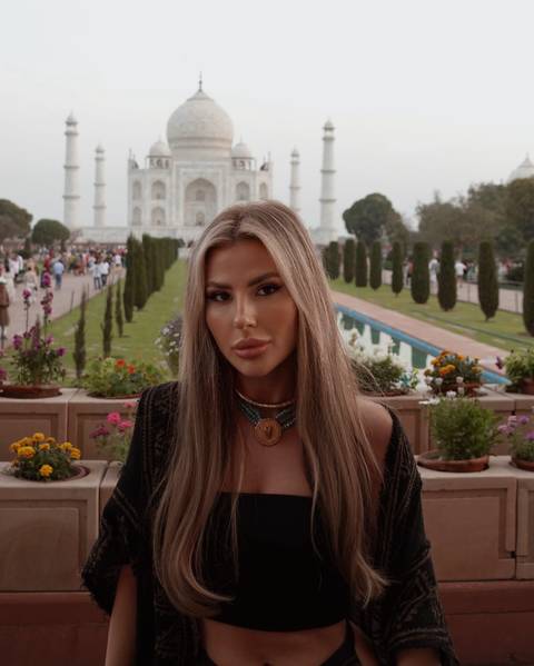 A person with Taj Mahal in the background, surrounded by gardens.