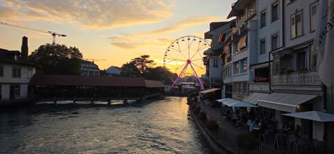       A sunset view over a river with a Ferris wheel and buildings
  
