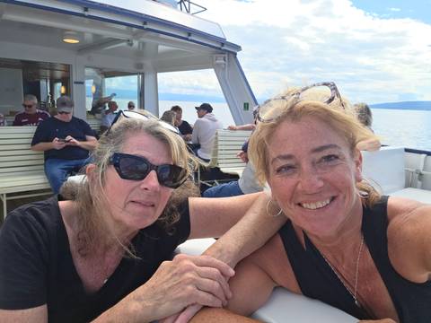       Two women on a boat with a lake and sky background
  