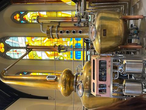 Interior of a distillery with copper stills and stained glass windows.