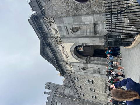 Tourists outside a historical castle with Gothic architecture.