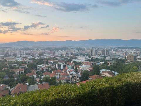 Panoramic view of a city at sunset with mountains in the background.