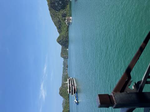       Boats anchored near limestone islands under a clear blue sky.
  