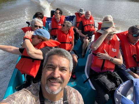 Group of people wearing life jackets enjoying a boat ride.