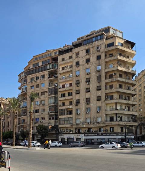       City buildings with balconies and air conditioning units.
  