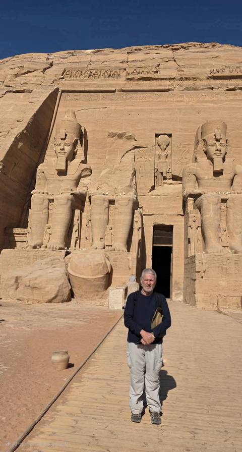       Statues carved into stone facade with a person standing in front.
  