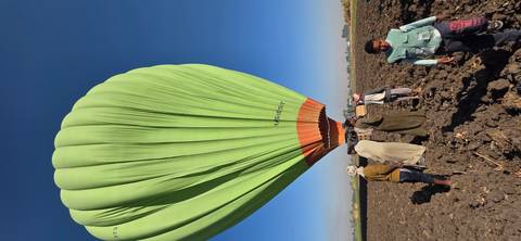 Hot air balloon on the ground with people standing nearby.