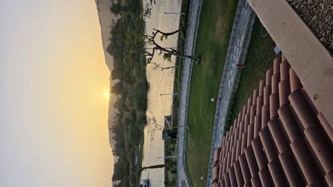       Sunset over a river with a landscaped garden.
  