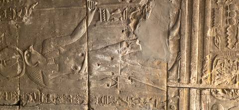       Relief carving on a stone wall depicting an Egyptian deity.
  